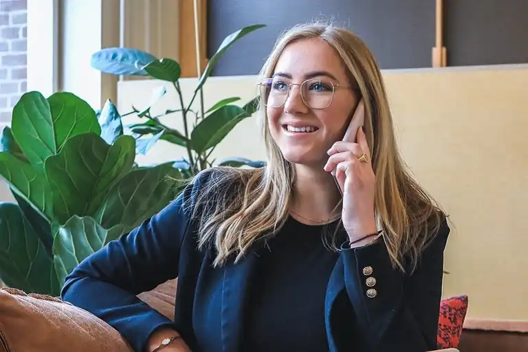 Donna che sorride mentre ascolta il messaggio di una segreteria